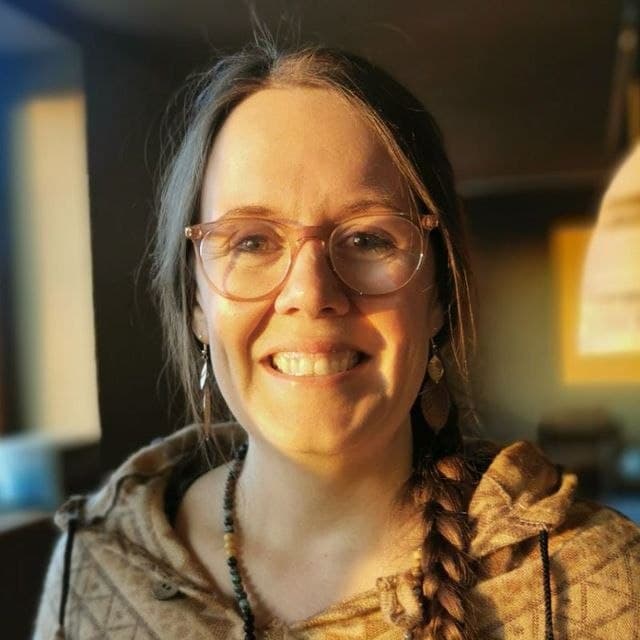 Kristina lacht in die Kamera, im Hintergrund ein Holzraum.